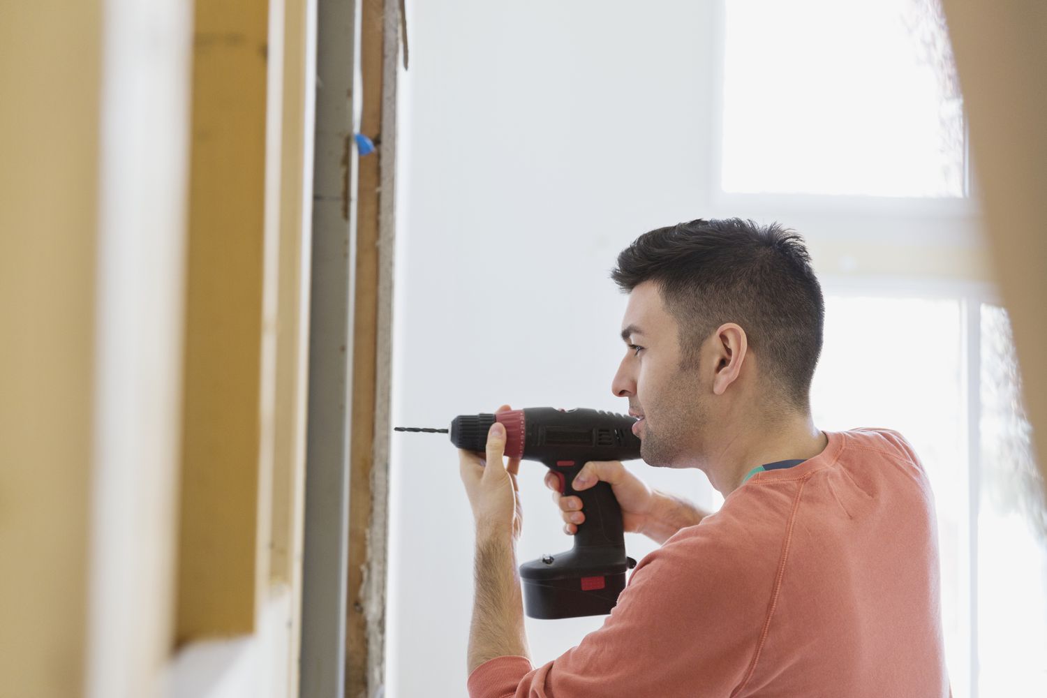 Homeowner drilling a hole into a wall