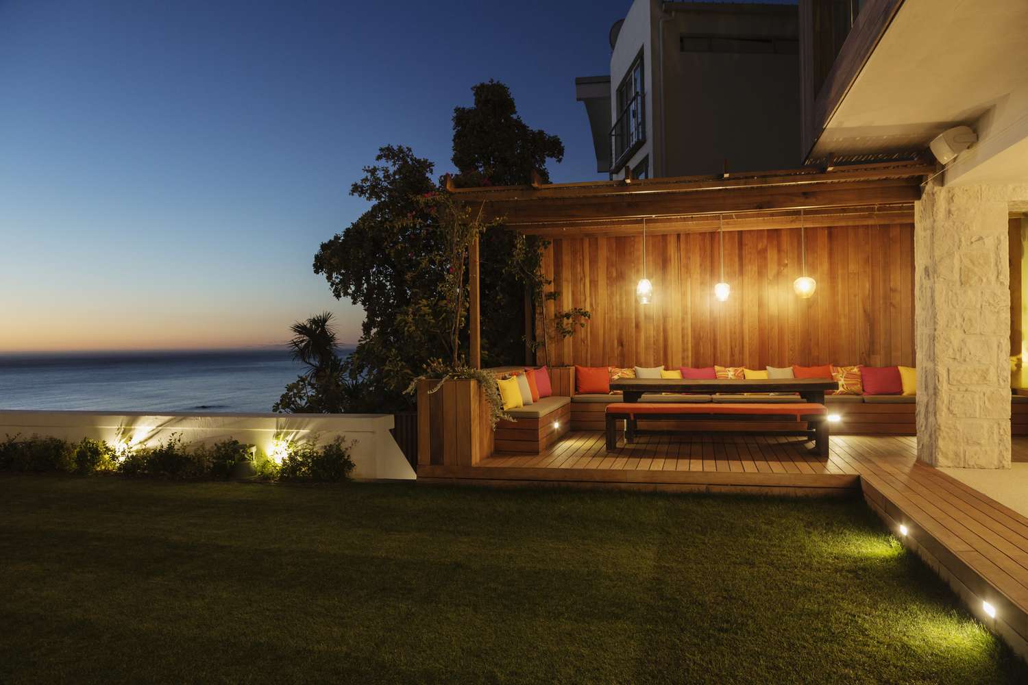 Lush backyard lawn and illuminated patio at dusk
